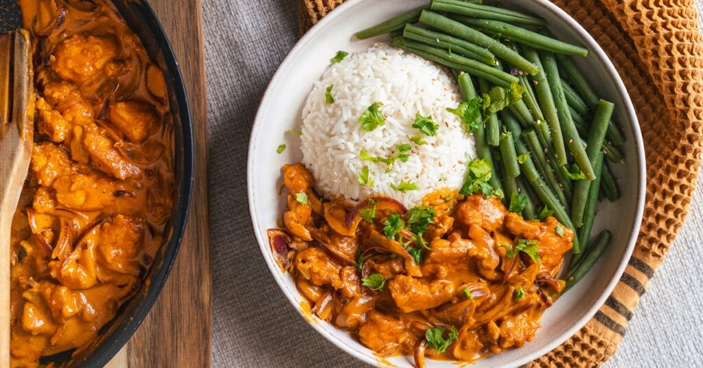 poêle à côté d'une assiette avec du tofu au four sauce coco riz et haricots