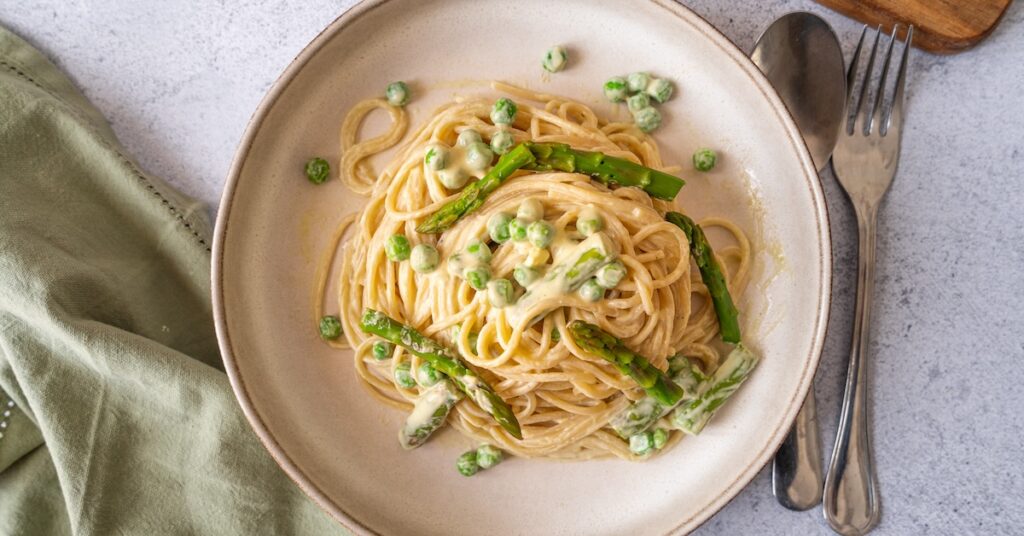 plat de spaghettis à la crème végétale, avec asperges vertes et petits pois