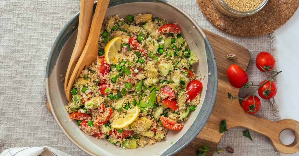 plat de taboulé maison réalisé avec des petits pois, de la menthe, de la feta, des tomates, des pistaches